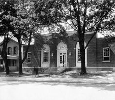 an old black and white photo of a school building with trees in front of it