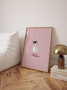 a pink poster with a white duck wearing sunglasses on the floor next to a lamp