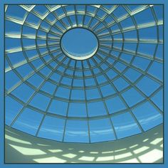 the inside of a circular glass structure with blue sky in the background