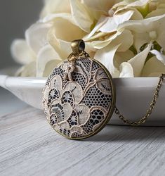 "The classic look of this lace pendant with initial charm makes it the perfect, personalized gift for her - this necklace is handmade with vintage beige lace that is actually antique in age since it's from the 1920s. It is made of cotton, as well as the black background fabric that is behind the lace. The gold color and clear crystal capital letter initial charm makes this a unique way to personalize the necklace as an anniversary gift for your wife or loved one's 13th year anniversary, which is the material lace, or the 2nd year anniversary, which is the material cotton. The pendant measures about 1.5 inches wide and the backing is a dark bronze color made of metal alloy. See the photos for popular chain length examples, or leave me a note at checkout for any custom length. Each piece of Delicate Medallion Necklace For Wedding, Delicate Cream Jewelry As A Gift, Delicate Cream Jewelry For Gift, Handmade Ornate Necklaces For Anniversary, Ornate Pendant Necklace For Anniversary, Handmade Cream Necklaces For Gifts, Cream Handmade Necklaces For Gifts, Antique Necklace With Large Pendant For Anniversary, Delicate Cream Necklace For Gift