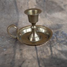 an antique brass candle holder on a wooden table