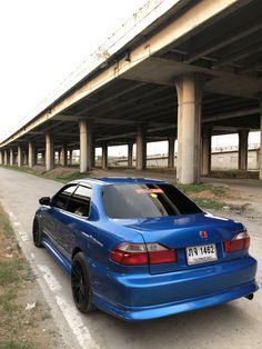 a blue car is parked in front of an overpass