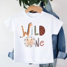 Wild One Safari Animals T-shirt T-shirt is 100% cotton.  We design & print our products with care & love! We use the best quality vinyls, inks & transfers on all products. * * * * * * * * * * * * * * * * * * * * * * * * * * * * * CARE INSTRUCTIONS: Wash inside out on gentle wash, Do not tumble dry. * * * * * * * * * * * * * * * * * * * * * * * * * * * * * SHIPPING: We want to get your product to you as quickly as possible, your purchase will be shipped through Australia post, Express post is available for selection. * * * * * * * * * * * * * * * * * * * * * * * * * * * * * GUARANTEE: We stand behind our products with a 100% guarantee; if you are unsatisfied with our product, please let us know & we will rectify any issues. We are unable to refund products due to change of mind or those tha Cotton Graphic Print T-shirt For Birthday, Fun Graphic Print T-shirt For First Birthday, Fun Cotton T-shirt For First Birthday, Playful Custom Print T-shirt For First Birthday, Casual T-shirt With Funny Print For First Birthday, Casual Graphic Print Shirt For First Birthday, Cotton T-shirt With Funny Print For Birthday, First Birthday Graphic Tee With Name Print, Playful Short Sleeve T-shirt For First Birthday