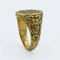 This Art Nouveau era yellow gold ring, dated inside 1900, is a fine example of the period's aesthetic, which often included fluid, organic forms and mythological motifs. The band features a figural depiction of Medusa, a nod to the era's fascination with Greco-Roman themes and figures, finely crafted from 15 karat yellow gold ring size 5 3/4, weighs 9.6 grams. The face of the ring presents a monogram or inscription, typical of personalization in jewelry of this time. Art Nouveau jewelry often reflected a departure from the rigid forms of the Victorian era, embracing instead the flowing lines and natural forms that have come to define the movement. All of our pieces are in as found condition, we just lightly clean them never polish, polish only upon request which nullifies the return option Symbolic Brass Rings For Formal Occasions, Ceremonial Antique Rings With Antique Finish, Gold Rings With Antique Finish For Wedding, Gold Wedding Ring With Antique Finish, Symbolic Intaglio Engraved Ring, Gold Art Nouveau Jewelry With Intaglio, Ceremonial Gold Art Nouveau Jewelry, Art Nouveau Yellow Gold Round Ring, Victorian Gold Engraved Collectible Ring