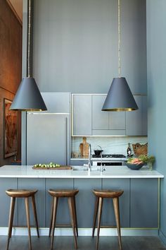 an image of a kitchen setting with bar stools in the foreground and two hanging lights over the island