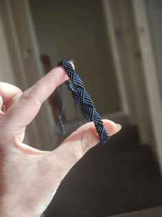 a hand holding a black and white braided object in it's left hand