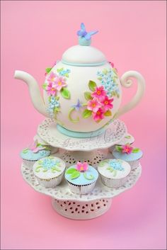 there is a tea pot and cupcakes on the cake stand with pink background