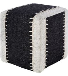 a black and white square ottoman sitting on top of a wooden floor next to a wall