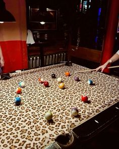 two people are playing pool on an old fashioned billiard table with leopard print cloth