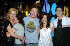 a group of young people standing next to each other in front of a neon sign