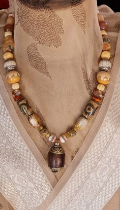 Welcome to my store. Please check all dimensions given. This large vintage Repoussé Tibetan bead is decorated with traditional pattened brass top and bottom. The palette for this necklace is warm and earthy. As well as a couple of my hand made beads, I have used inlaid agate in the style of Tibetan Dzi beads, Afghan Calcite, Superb antique African trading beads, Picture Jasper, pumpkin carved bone beads, polished river stone  and carnelian spacers. This is a 'One of a Kind' As stated in other posts, I can lengthen or shorten to suit and earrings can be made to accompany. Take a look at my personalization policy. Traditional Brown Beaded Pendant Necklace, One Of A Kind Vintage Brown Jewelry, Bohemian Amber Necklace With Wooden Beads, Traditional Brown Jewelry For Festivals, Spiritual Brown Beaded Necklaces For Festivals, Festival Style Brown Beads, Brown Artisan Jewelry For Festivals, Artisan Brown Jewelry For Festivals, Brown Large Beads Jewelry For Festivals