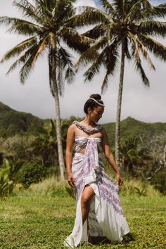 a woman in a dress standing next to two palm trees