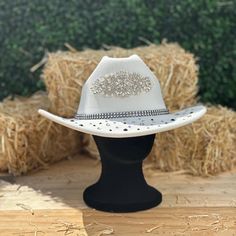 a white cowboy hat sitting on top of a wooden table next to hay bales