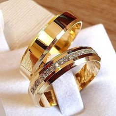 two gold wedding rings sitting on top of a white napkin next to an empty napkin