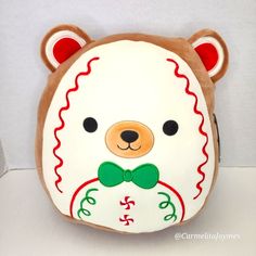 a brown and white teddy bear with a green bow tie on it's head