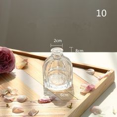 there is a bottle on the table next to some flowers and petals in front of it