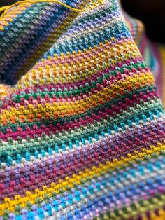 a multicolored crocheted blanket laying on top of a table