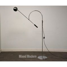 a floor lamp with a metal base and a black light bulb on the end, in front of a white wall