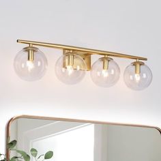 three light bathroom fixture with clear glass globes on the top and gold metal frame