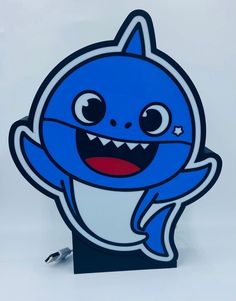 a blue and white sticker with a smiling shark on it's face, in front of a white background