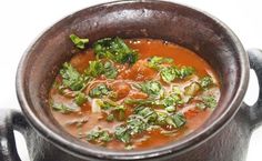 a wooden bowl filled with soup on top of a table