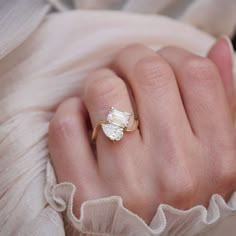 a woman's hand wearing a gold ring with an oval shaped diamond on it