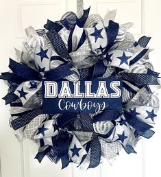 a wreath with the word dallas cowboys on it hanging from a front door decorated with blue, white and silver ribbons