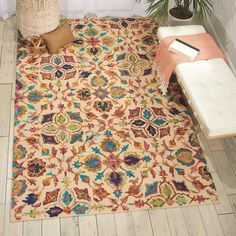 an area rug with various colors and designs on the floor next to a potted plant