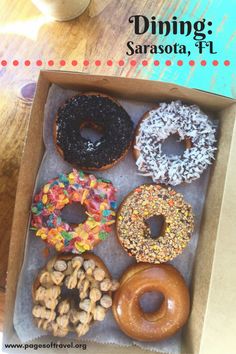 a box filled with assorted donuts on top of a wooden table