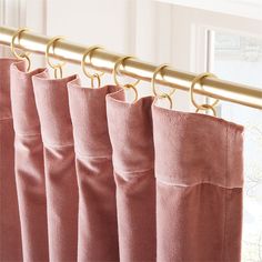 pink curtains hanging on a gold rod in front of a window