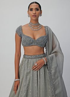 Introducing the stunning Grey Crystal and Sequin Embroidered Organza Lehenga Set, a masterpiece of craftsmanship that effortlessly blends traditional elegance with modern sophistication. Made from a luxurious mix of organza and georgette, the grey lehenga is intricately hand-embroidered, featuring shimmering sequins and crystal embellishments that add a dazzling, eye-catching effect. Paired with a jewelled blouse adorned with exquisite crystal detailing, this set exudes timeless beauty and charm. The look is completed with a delicately embroidered dupatta that enhances the outfit’s opulent design. Perfect for weddings, receptions, or festive occasions. Composition : Lehenga, Dupatta - Organza and Blouse - Georgette Care: Dry Clean Only and Vacuum Storage This product can be customized for Fitted Organza Pre-draped Saree With Dupatta, Designer Wedding Pre-draped Saree With Dupatta, Festive Hand Embellished Organza Pre-draped Saree, Organza Choli For Diwali Reception, Organza Choli For Reception And Diwali, Organza Set With Traditional Drape For Reception, Organza Sets With Traditional Drape For Reception, Traditional Drape Organza Set For Reception, Hand Embellished Organza Traditional Wear For Reception