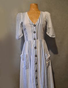 This cute dress can easily be dressed up or down.  It not only has 10 adorable buttons down the front but it has pockets as well.   Bust= 30in Waist= 28in (stretches) Shoulder to hem= 42in Sleeve= 12in Fitted Button-up Midi Dress With Pockets, Short Sleeve Cotton Dresses With Buttoned Pockets, Cotton Button-up Dress For Day Out, Cotton Dresses With Buttoned Pockets And Short Sleeves, Casual Beach Dress With Button Cuffs, Cotton Midi Dress With Button Closure For Day Out, Casual V-neck Dresses With Button Cuffs, Cotton Button-up Midi Dress For Day Out, Casual Cotton Midi Dress With Buttons