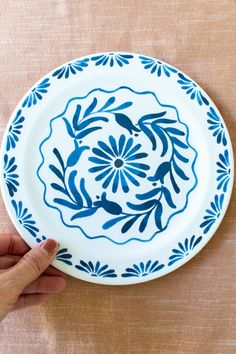 a hand is holding a blue and white plate