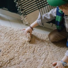 a person kneeling down on the floor with a rug in front of them and one hand reaching for something