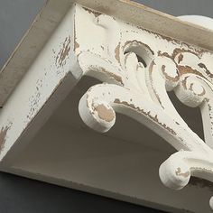 an old white painted shelf with decorative designs