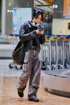 a man in black jacket and jeans holding a cell phone