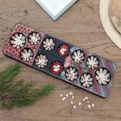 a wooden table topped with a tray filled with flowers and seeds next to a book