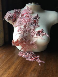 a white mannequin with pink and red flowers on it's back, sitting on a wooden floor