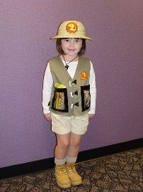 a young boy wearing a fireman's hat and vest standing in front of a purple wall