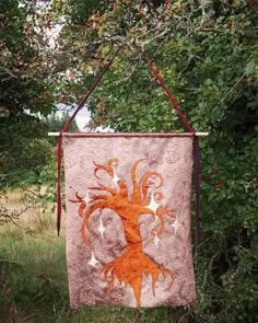 an orange and white quilt hanging from a tree