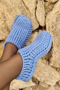 a woman's legs wearing blue knitted slippers on top of rock formations