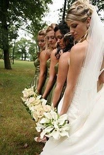 a bride and her bridesmaids are standing in the grass with their bouquets