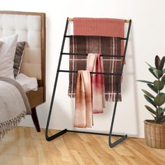 a rack with blankets hanging on it next to a bed