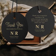 two black and gold wedding tags with thank you written on them, hanging from twine strings