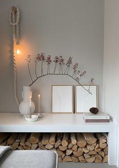 a white table topped with lots of logs next to a wall mounted candle and pictures