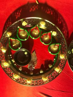 a metal tray with candles on it sitting on a red table cloth covered tablecloth