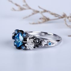 Graceful and glamorous, this skull ring delivers eye-catching style. A blue princess cut stone shimmers at the center of this style, while four round stones encircled in heart-shaped frames, adding elegance and femininity to the design. Two skulls flank the centerpiece,creating a truely distinctive look. Sparkling with the excitement of the moment, beautiful flowers on this design blooms with your love. This skull and flower ring is a romantic choice for everyday wear or special occasion.Carat W Pretty Trinkets, Flower Wedding Ring, Character Clothing, Skull Flower, Heart Shaped Frame, Black Skull, Flower Skull, Black Skulls, Flower Wedding