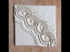 an intricately designed tile on a wooden surface, with white paint and lacework