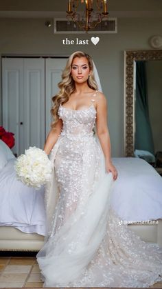 a beautiful woman in a wedding dress standing next to a bed with flowers on it