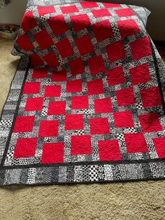 a red and black quilt sitting on top of a bed